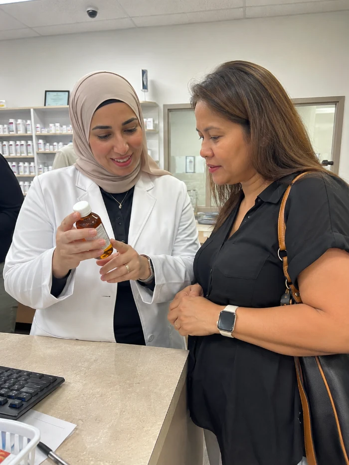 Pharmacist showing a compounded liquid medication bottle to a patient during a post-bariatric medication consultation